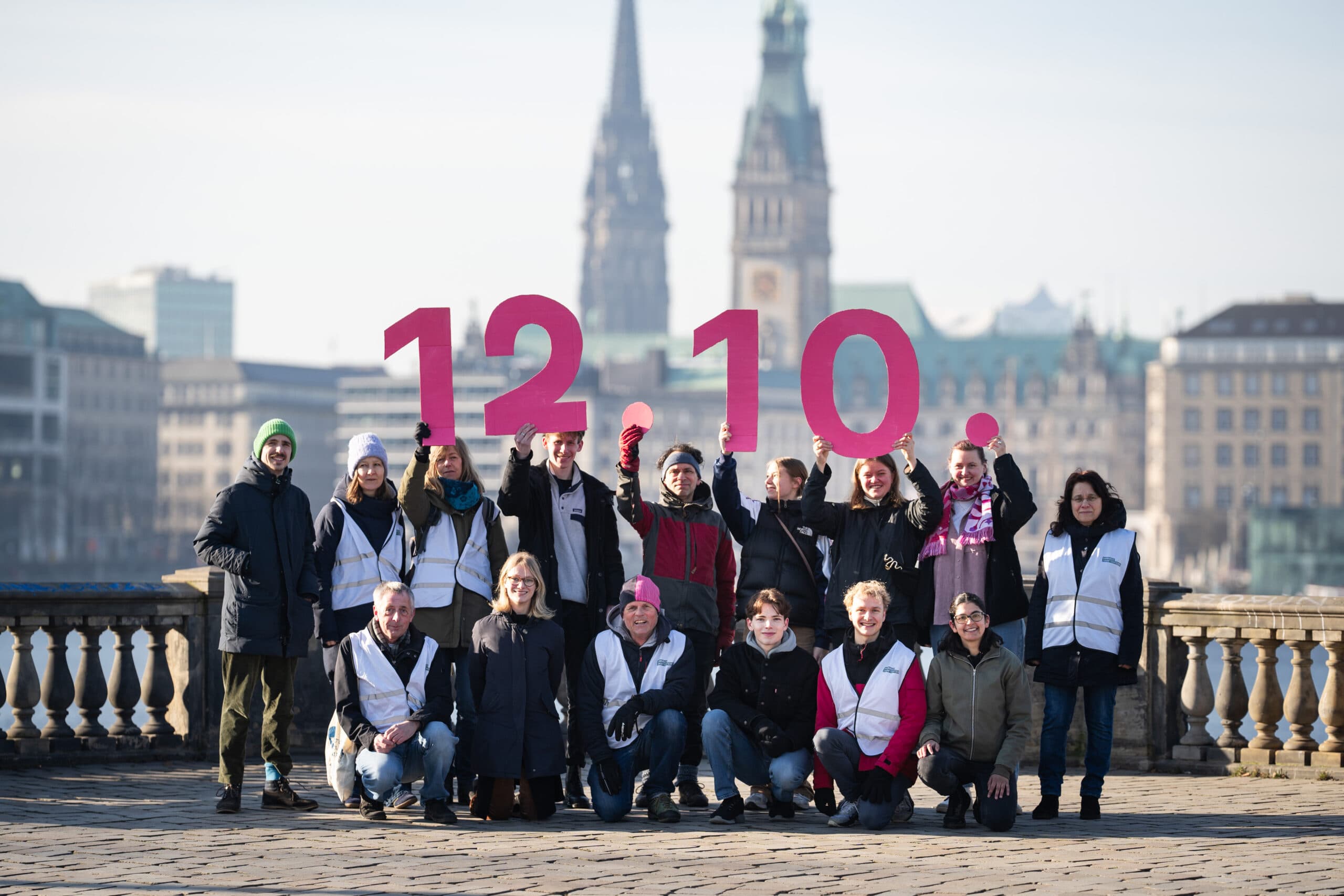 Unterstüter*innen des Hamburger Zukunftsentscheids vor der Binnenalster halten Schilder mit dem Datum 12.10. hoch